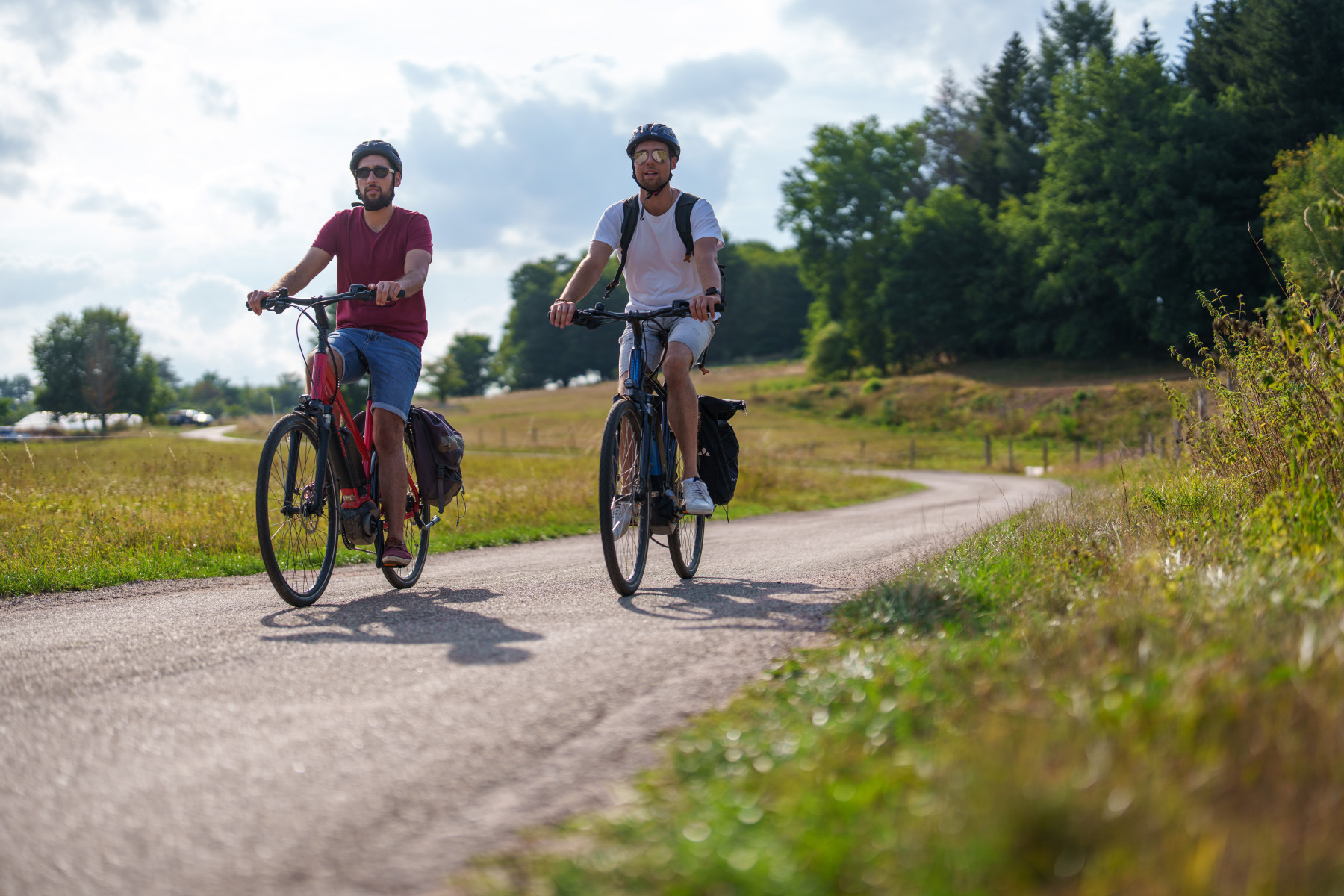 Photo de deux personnes faisant du vélo sur une route enrobée par temps ensoleillé