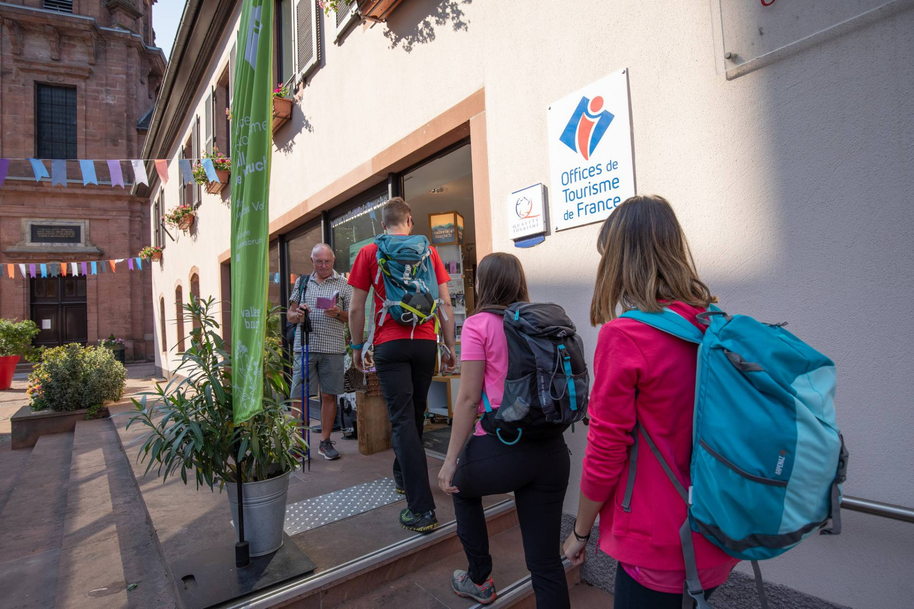 Groupe de randonneurs entrant dans l'office de tourisme de la vallée de la Bruche par temps ensoleillé